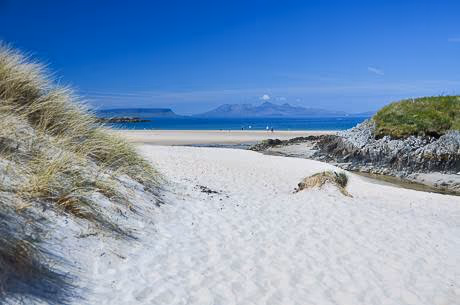 A path through marram grass onto the white sand at Arisaig, islands across the water