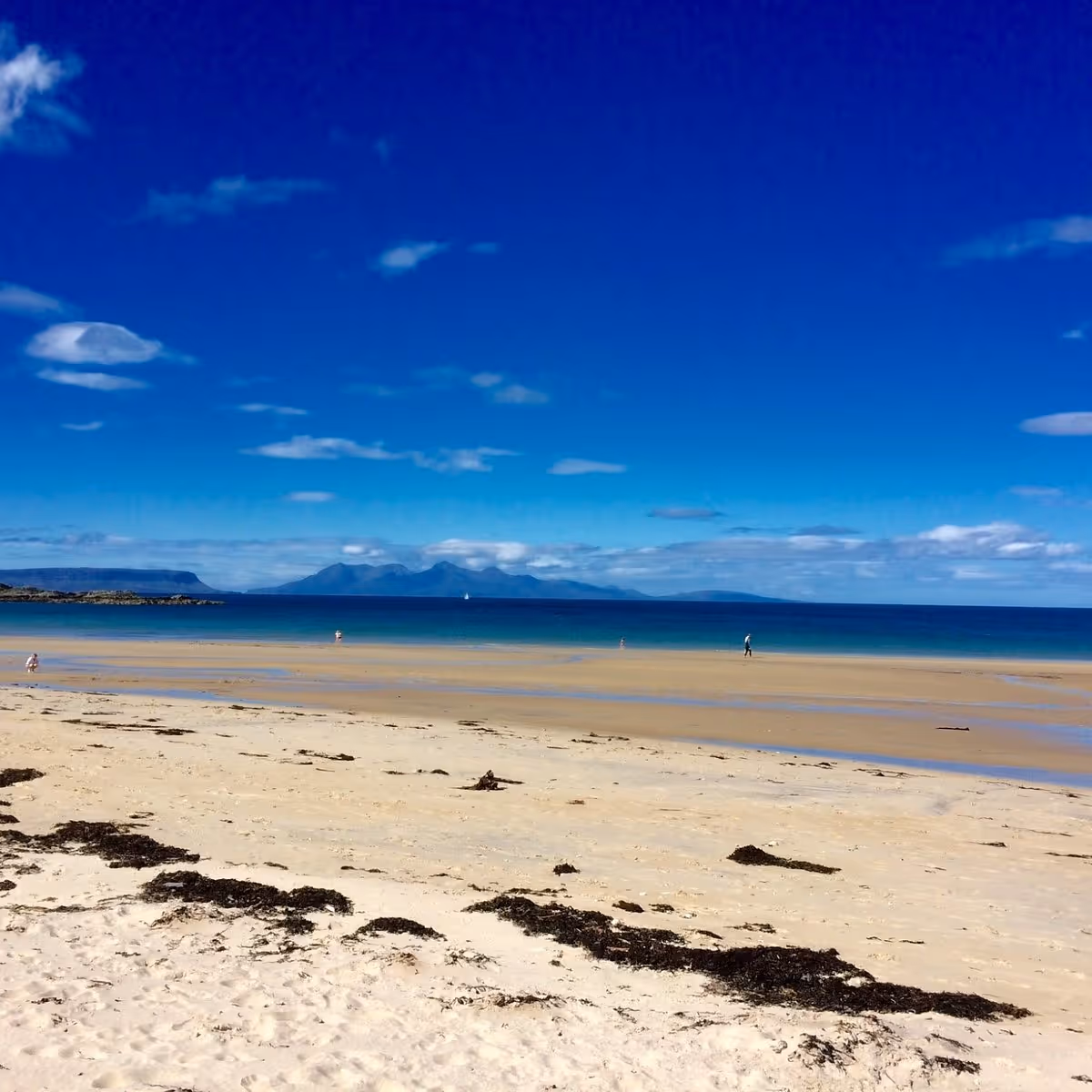 White shell sand and turquoise water at Camusdarach, with the Small Isles on the horizon
