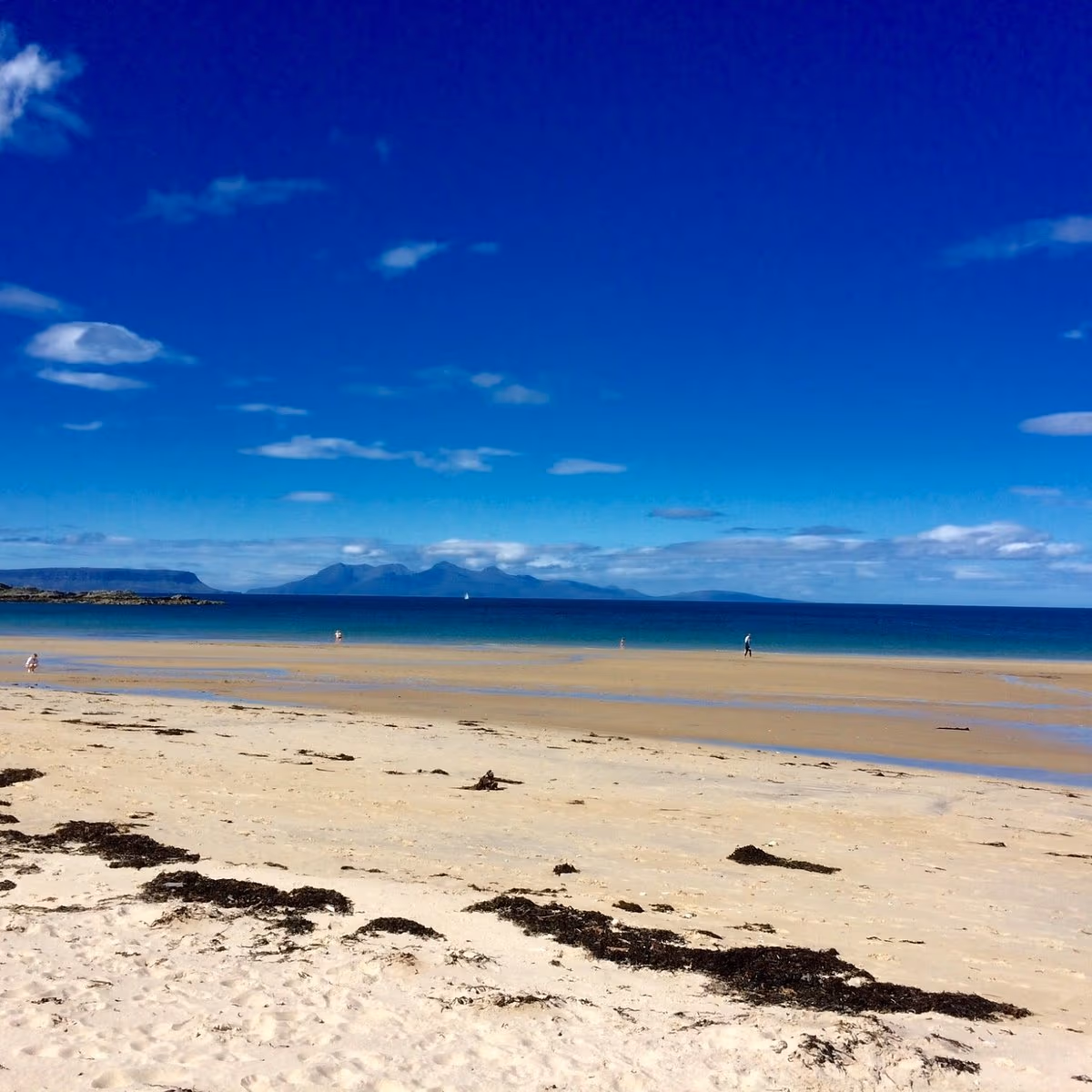 White shell sand and turquoise water at Camusdarach, with the Small Isles on the horizon