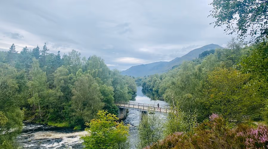 A footbridge over the river below Dog Falls, the glen and its hills opening out beyond