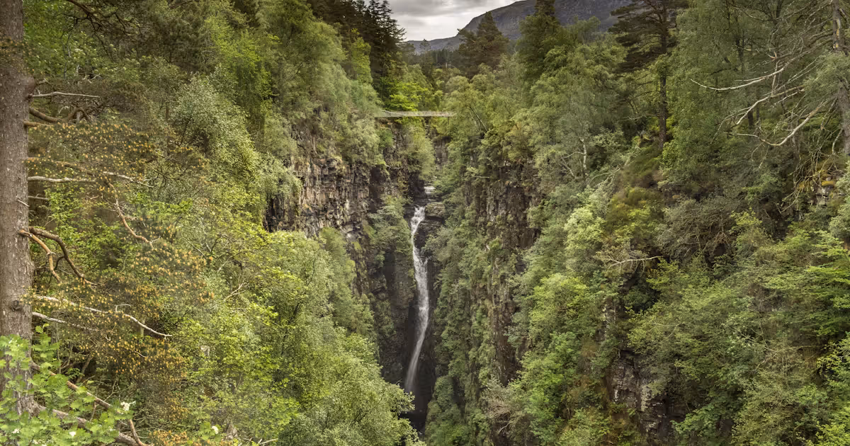 The Victorian suspension bridge strung across Corrieshalloch Gorge, the drop falling away below it into the trees