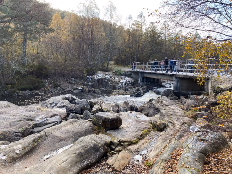 Walkers on the footbridge at Dog Falls, with the river running white through the rocks below