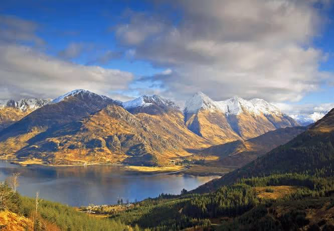 The Five Sisters of Kintail with snow on the tops, standing over Loch Duich and the forestry below
