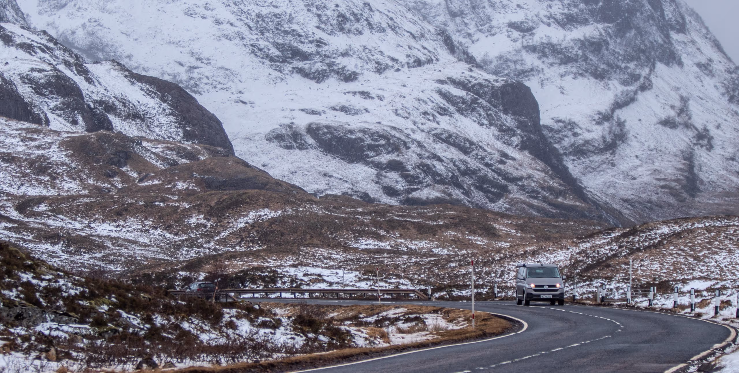 Glen Coe under snow, the road running along the foot of the ridge with the tops white above it