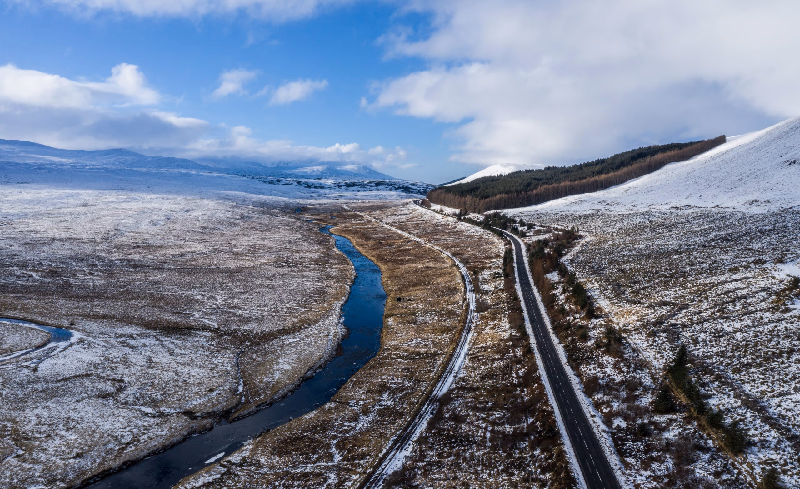 The road through Glen Shiel under snow, a river winding beside it between white hills
