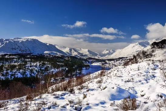 Glen Affric deep in snow under a blue sky, the loch dark between white hills