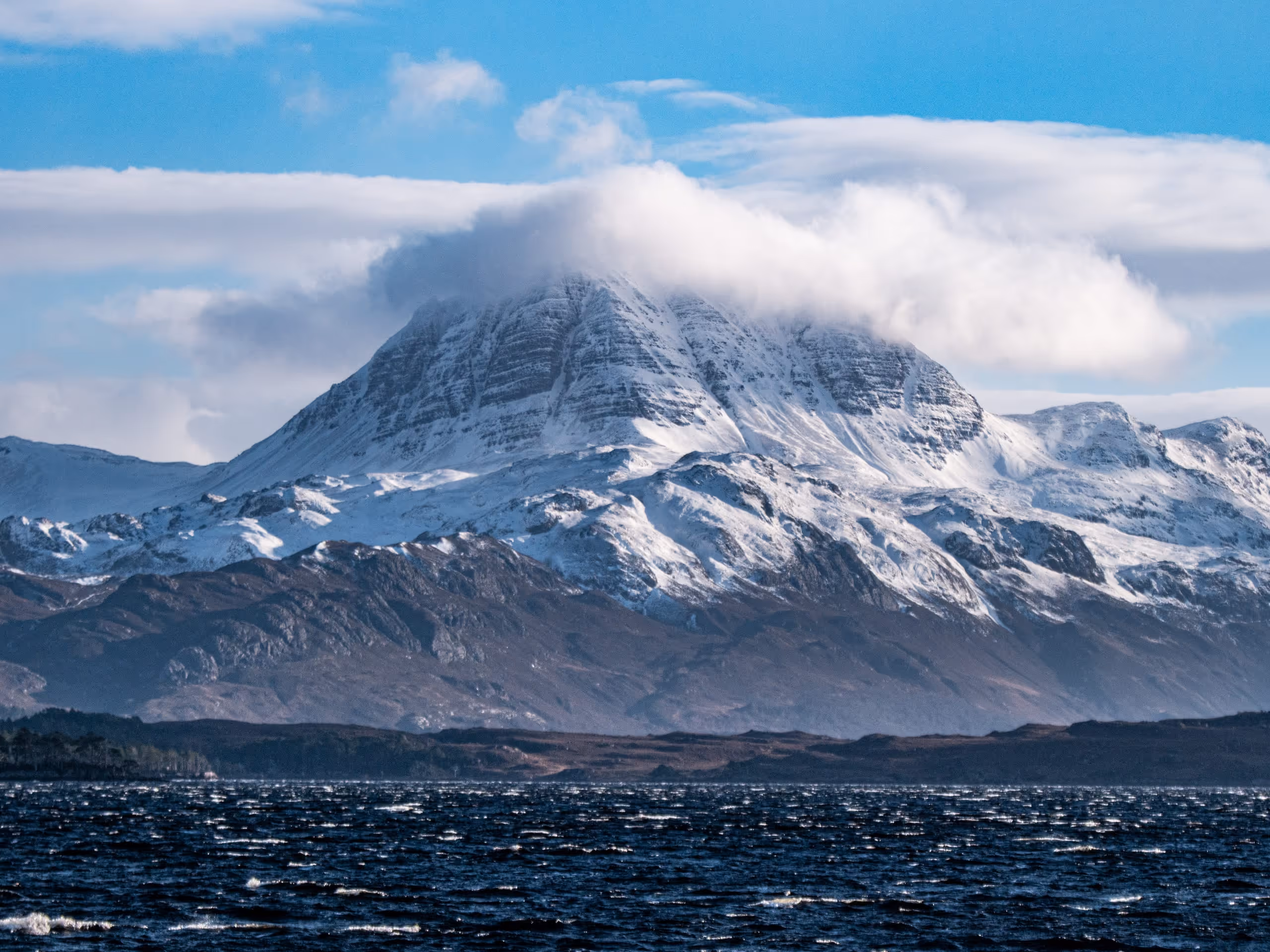 Slioch standing over Loch Maree with snow down its face, the loch dark along the foot of the mountain