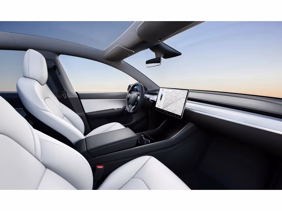 The white interior of the car from the back seat, glass roof overhead