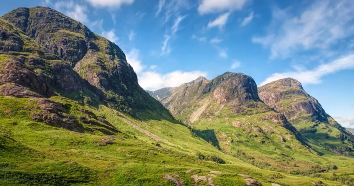 The Three Sisters standing over Glen Coe under a clear sky, the three ridges dropping one behind another into the glen