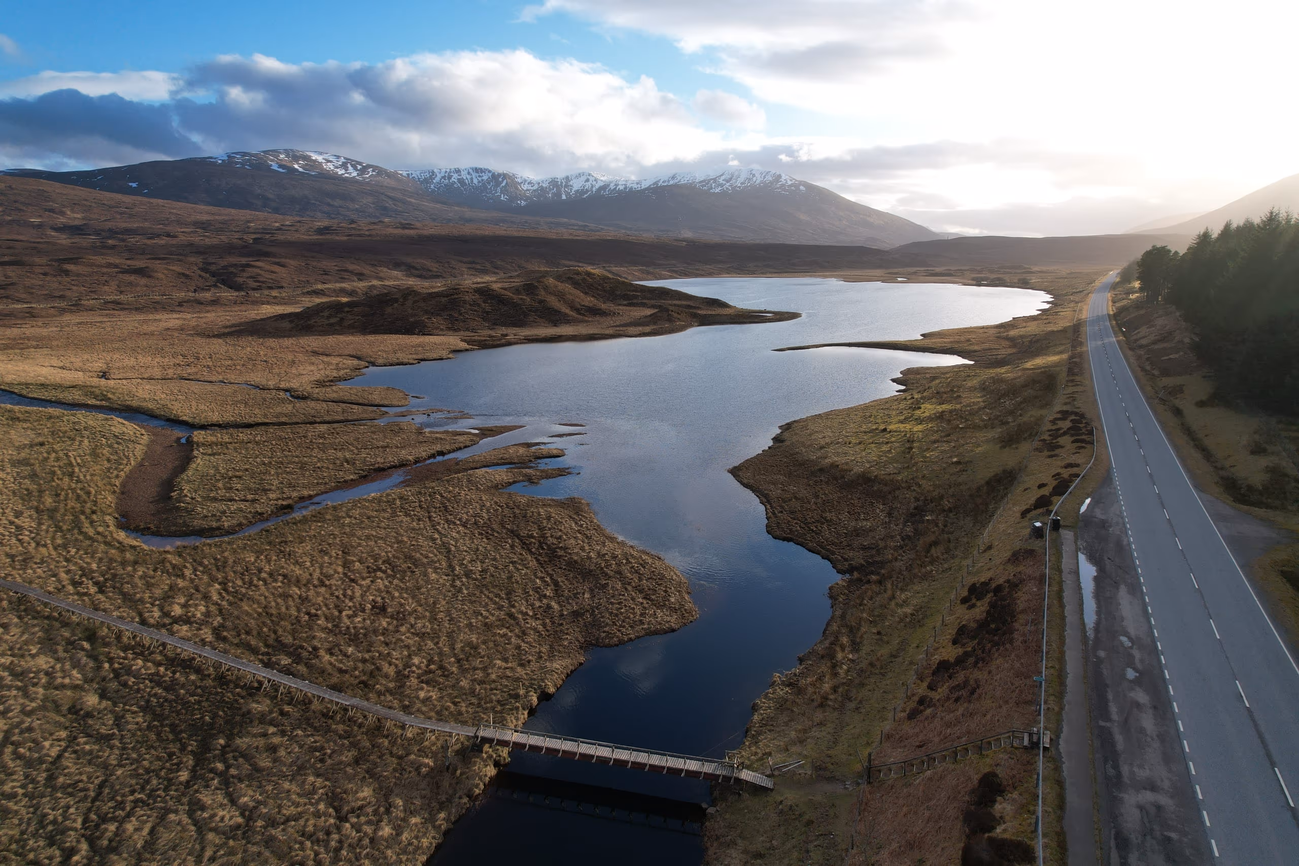 The road through Glen Torridon seen from above, curving beside a river between snow-streaked hills